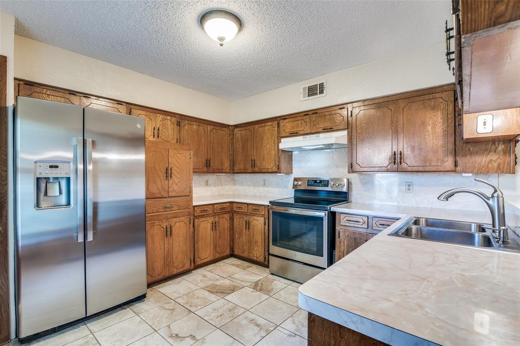805 Paul Wilson Road Wylie, TX 75098 - Photo 4 of 38 Kitchen features breakfast bar, ample cabinets for storage, and tile flooring.