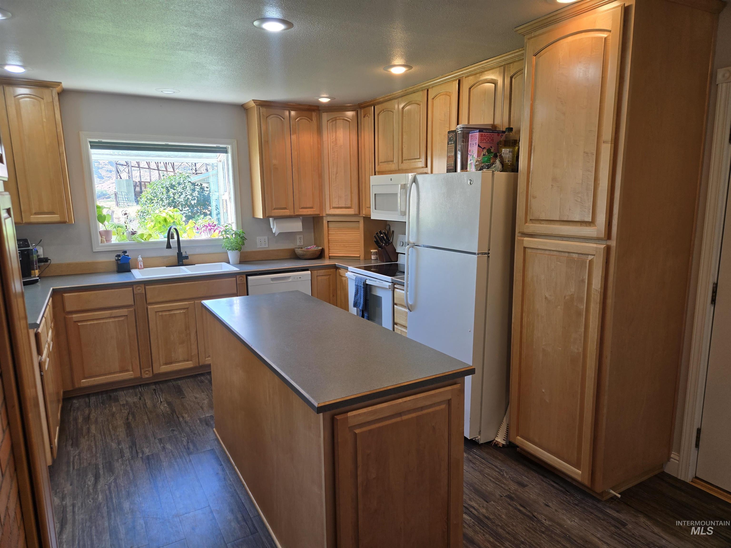 17082 Snake River Road Asotin, WA 99402 - Photo 2 of 31 Kitchen featuring white appliances, dark wood finished floors, recessed lighting, a center island, and light brown cabinetry