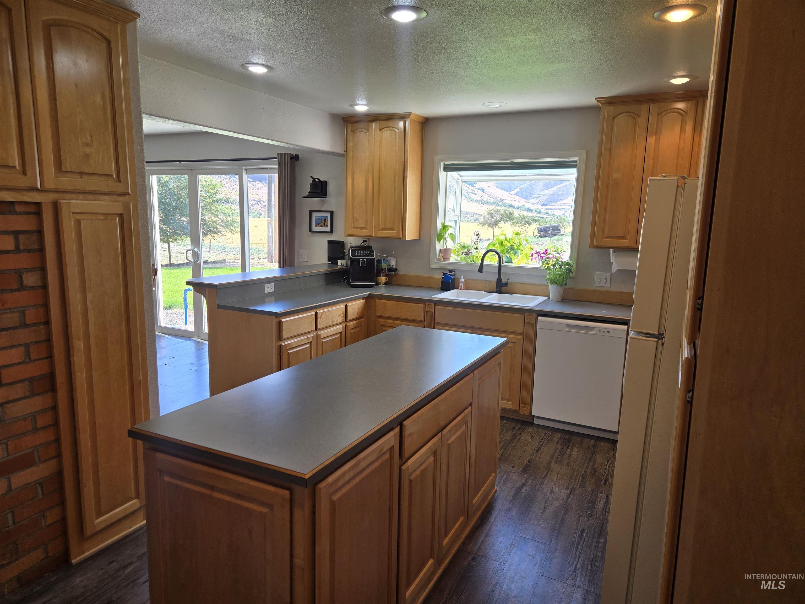 17082 Snake River Road Asotin, WA 99402 - Photo 3 of 31 Kitchen featuring white appliances, a peninsula, a textured ceiling, healthy amount of natural light, and dark wood-style floors