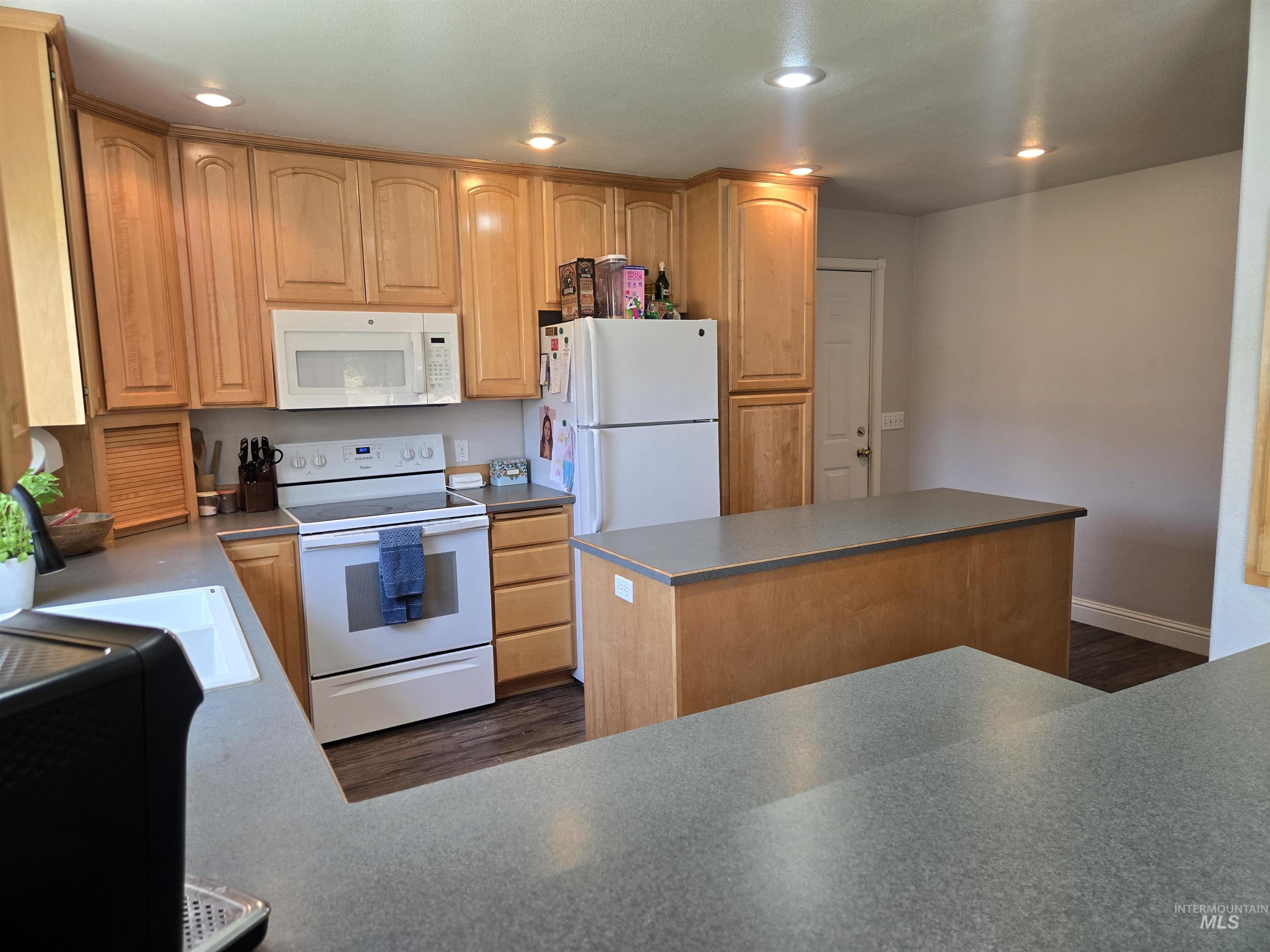 17082 Snake River Road Asotin, WA 99402 - Photo 6 of 31 Kitchen featuring white appliances, light brown cabinets, dark wood-style floors, recessed lighting, and a center island