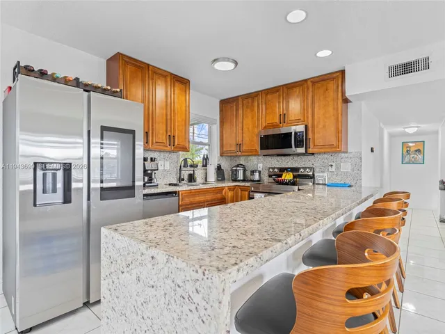 a large kitchen with stainless steel appliances granite countertop a stove a sink and a microwave