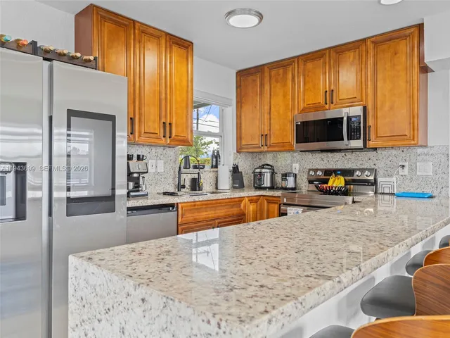 a kitchen with stainless steel appliances granite countertop a stove a sink a microwave a refrigerator and cabinets