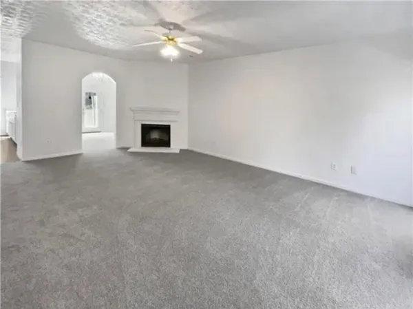 an empty room with a fireplace and ceiling fan