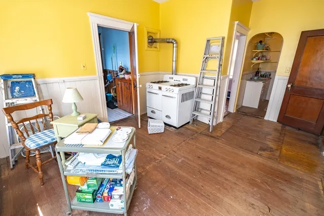 a view of a dining room with furniture one side kitchen view and wooden floor