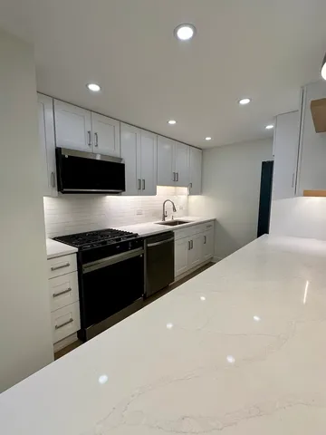 a large kitchen with stainless steel appliances a large counter top