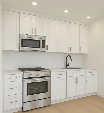a kitchen with white cabinets and stainless steel appliances