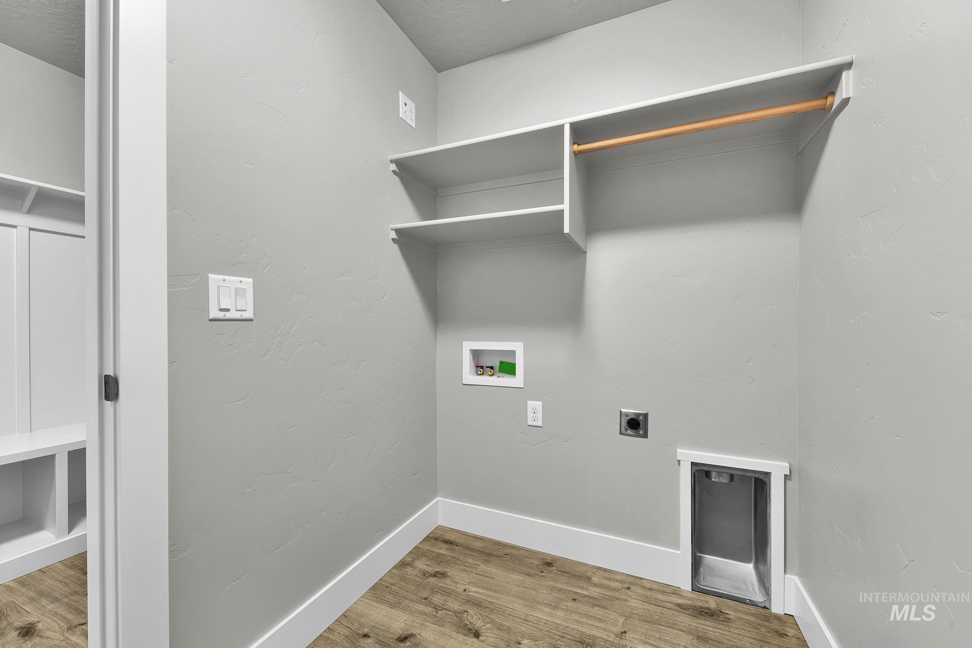 320 North 12th Parma, ID 83660 - Photo 13 of 34 Utility room featuring wood-finish flooring, light gray walls, white baseboards, and built-in white shelving with a wooden hanging rod