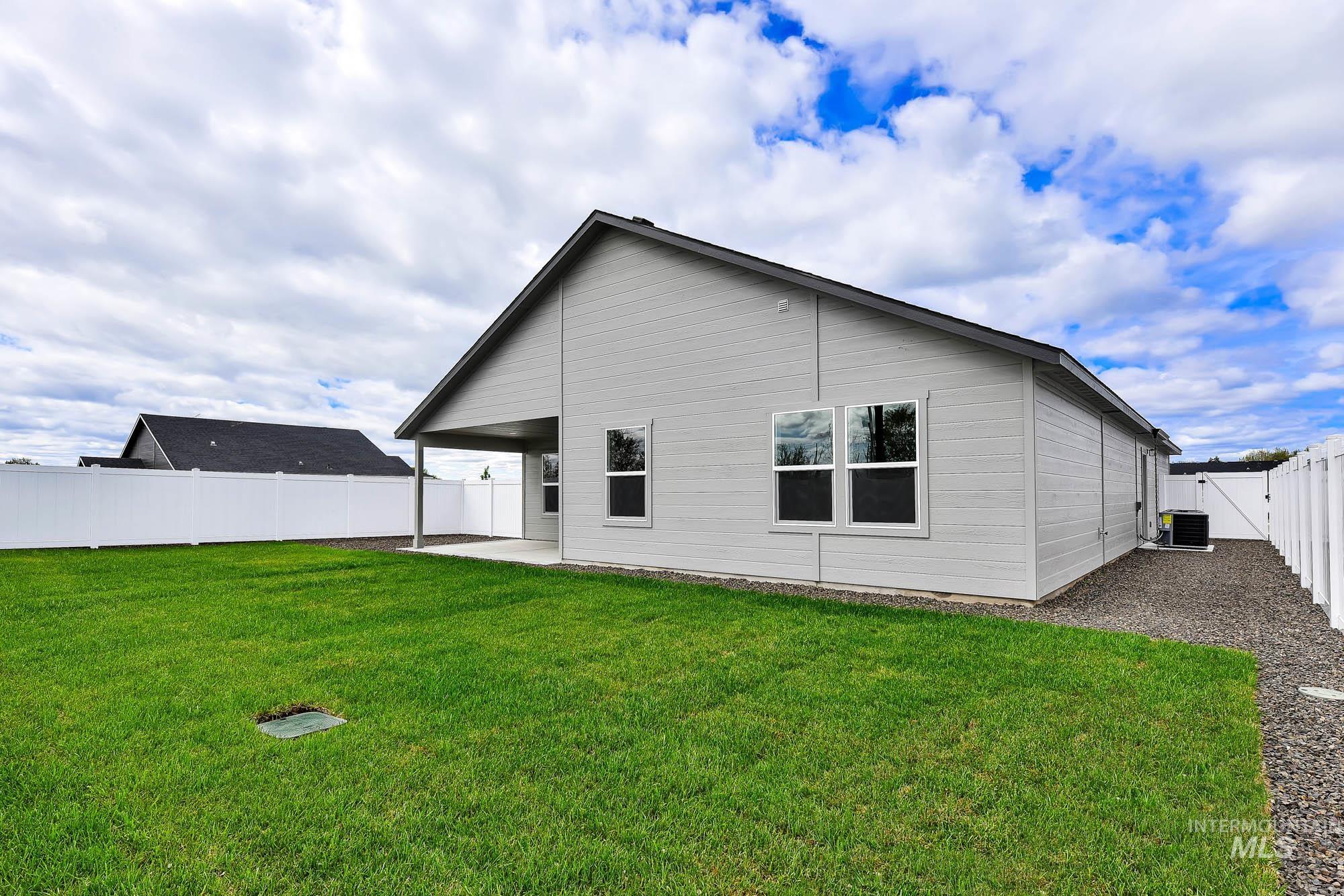 320 North 12th Parma, ID 83660 - Photo 16 of 34 Expansive backyard with a manicured lawn, white vinyl fencing, and a covered patio area