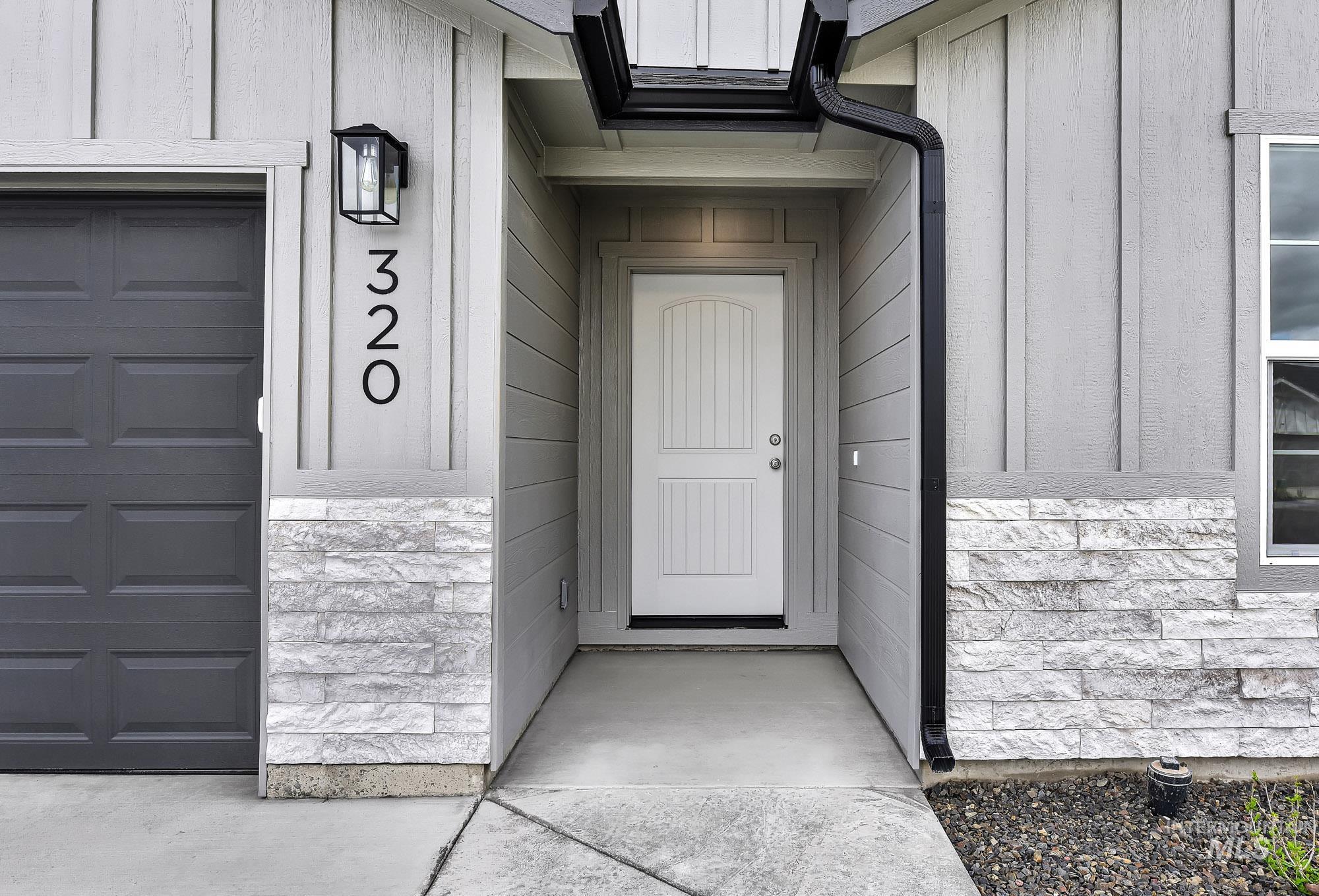 320 North 12th Parma, ID 83660 - Photo 17 of 34 Welcoming entry featuring a paneled white door, board and batten siding, horizontal siding, and a stone facade