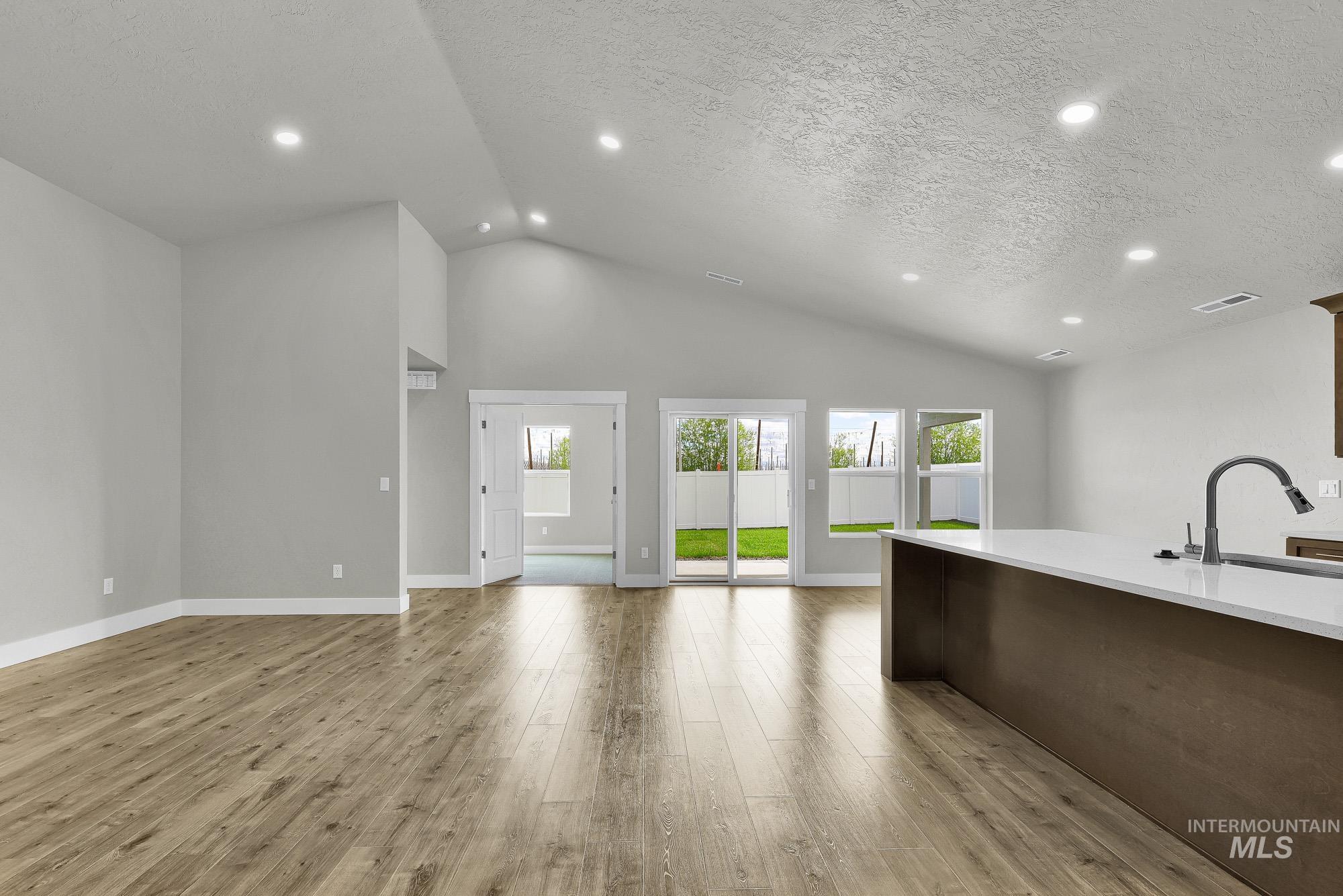 320 North 12th Parma, ID 83660 - Photo 18 of 34 Spacious open-concept living area featuring vaulted ceilings, recessed lighting, and wood-finish flooring