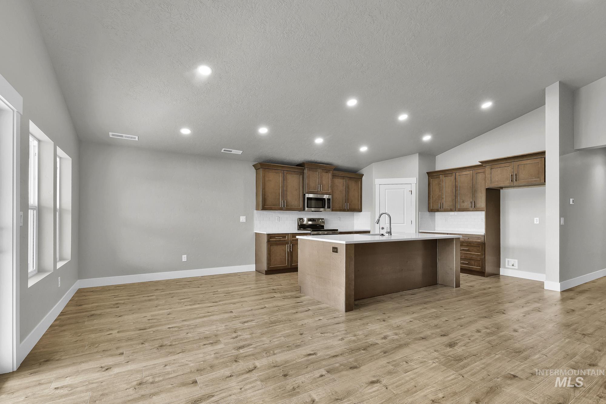 320 North 12th Parma, ID 83660 - Photo 20 of 34 Open-concept living space featuring wood-finish flooring, recessed lighting, and a kitchen with wood cabinetry, light countertops, and a central island