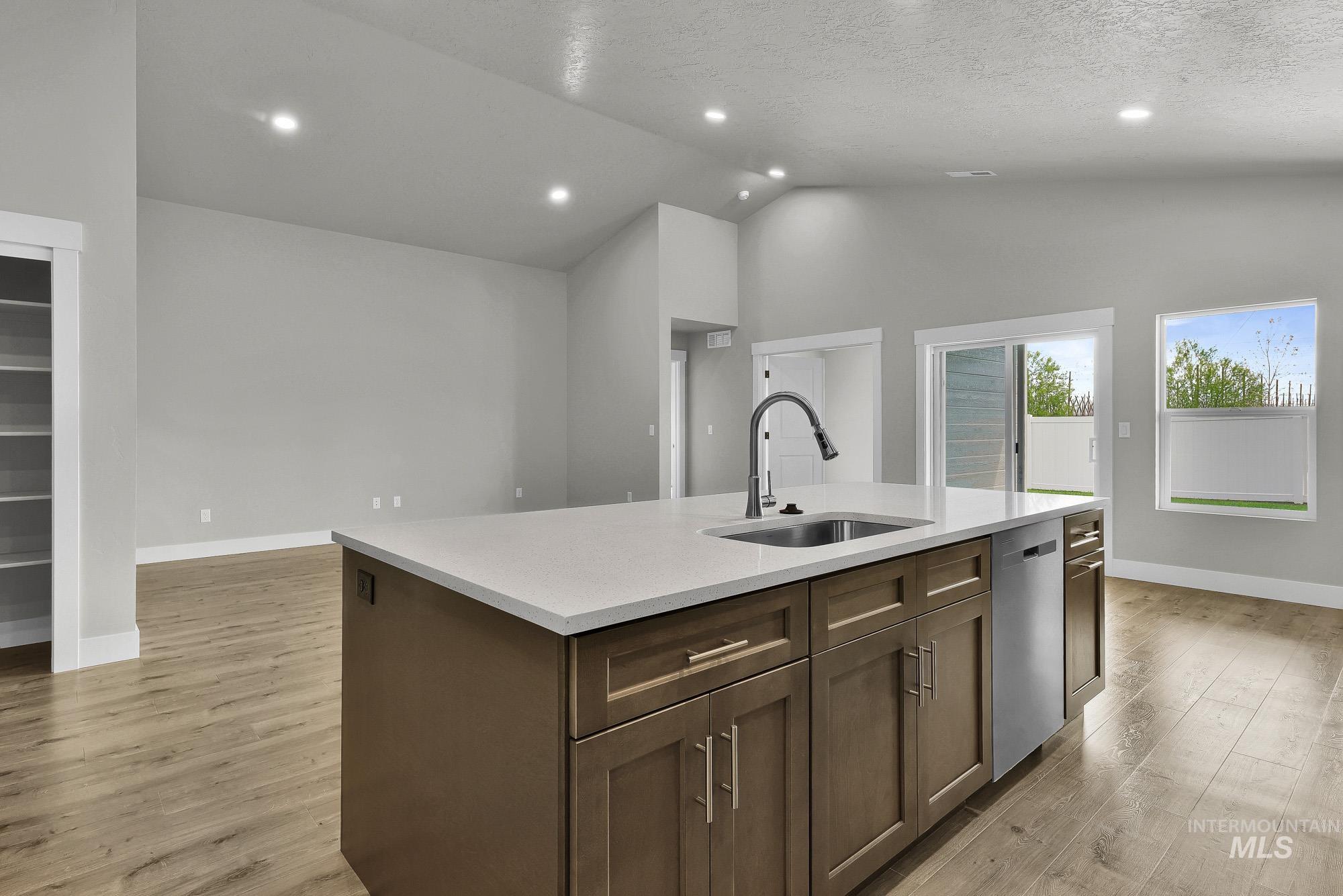 320 North 12th Parma, ID 83660 - Photo 22 of 34 Kitchen island featuring a single-basin sink with a gooseneck faucet, light-toned countertop, and brown cabinetry