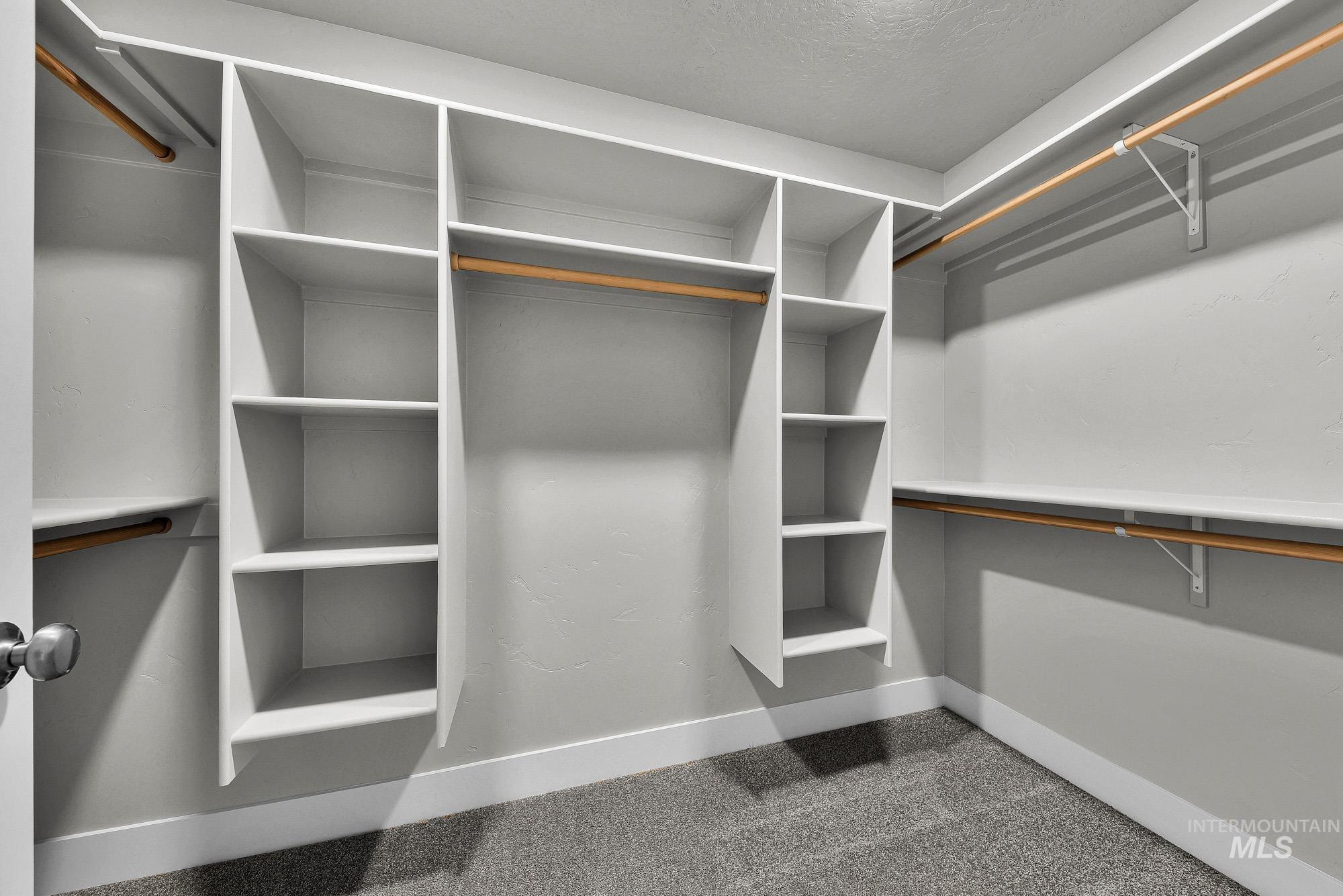 320 North 12th Parma, ID 83660 - Photo 26 of 34 Walk-in closet featuring built-in shelving, multiple hanging rods, white trim, and gray carpeting