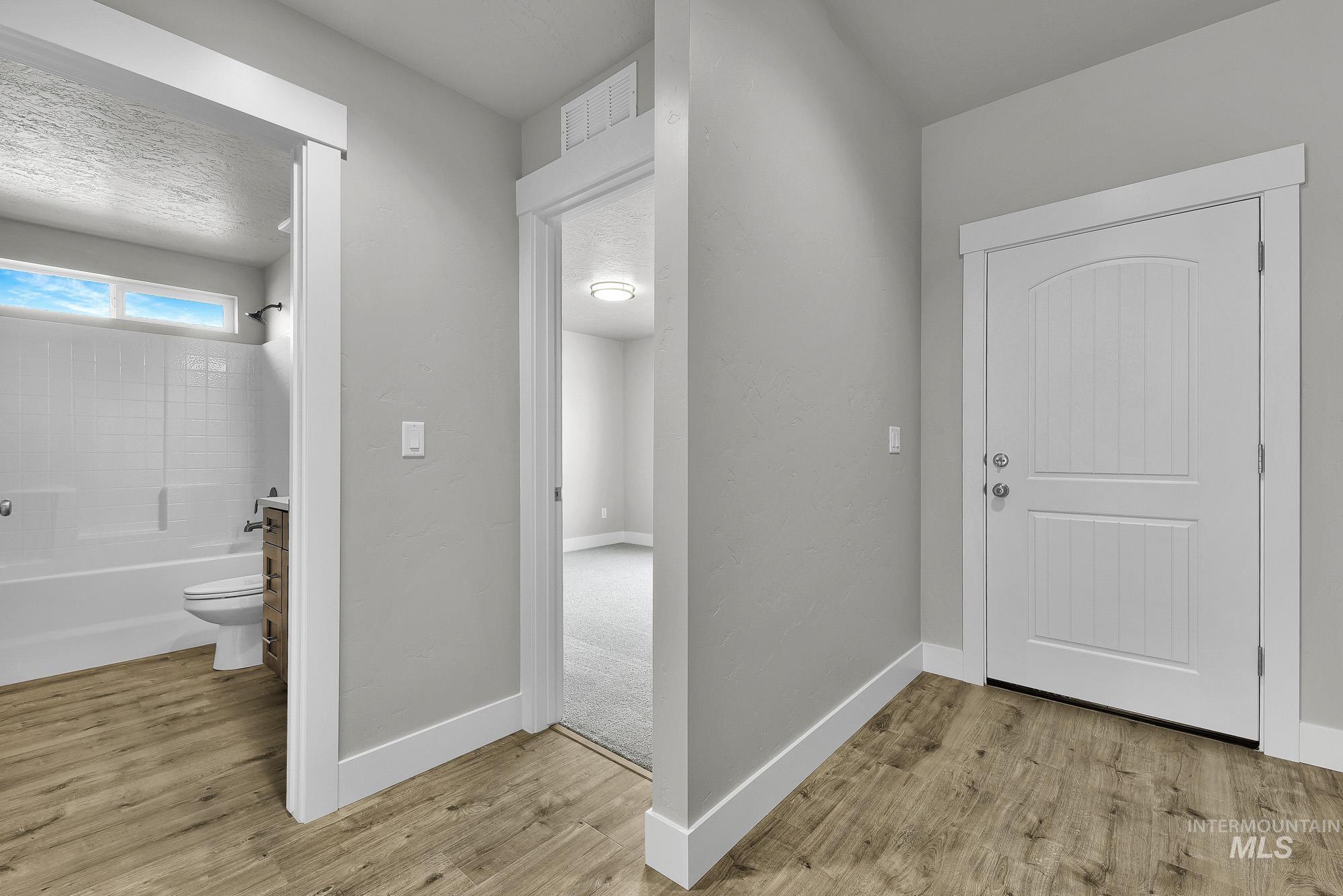 320 North 12th Parma, ID 83660 - Photo 30 of 34 Entryway featuring wood-finish flooring, a white paneled door with an arched top, and crisp white trim