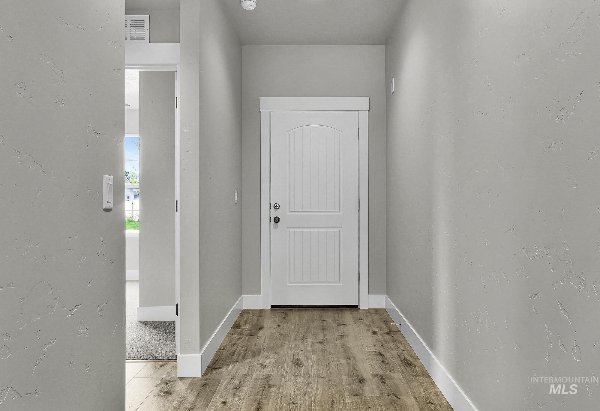 320 North 12th Parma, ID 83660 - Photo 3 of 34 Entryway featuring wood-finish flooring, light gray wall finishes, white baseboards, and a white two-panel door with an arched top