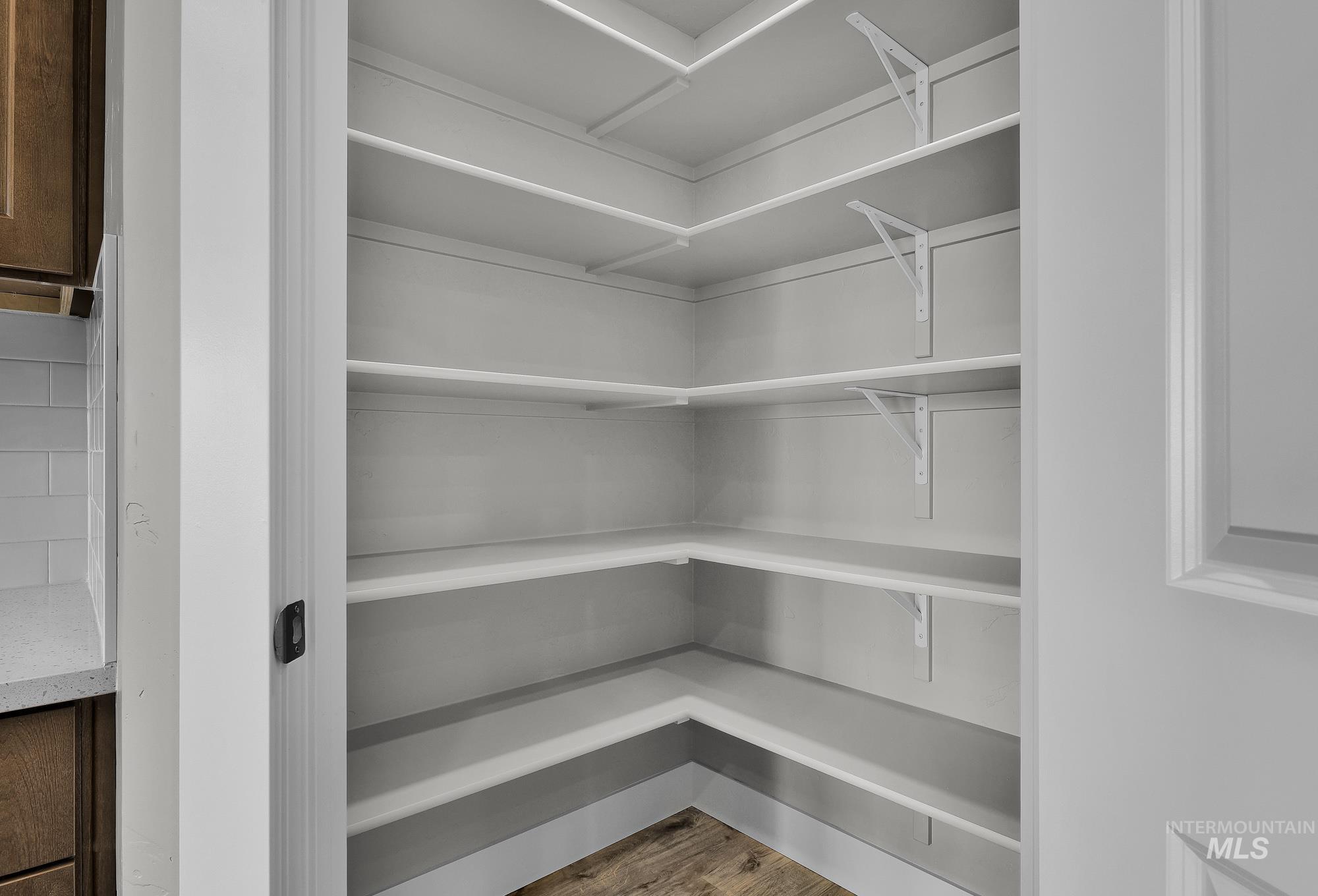 320 North 12th Parma, ID 83660 - Photo 9 of 34 Walk-in pantry with extensive white shelving, wood-finish flooring, and a white interior door
