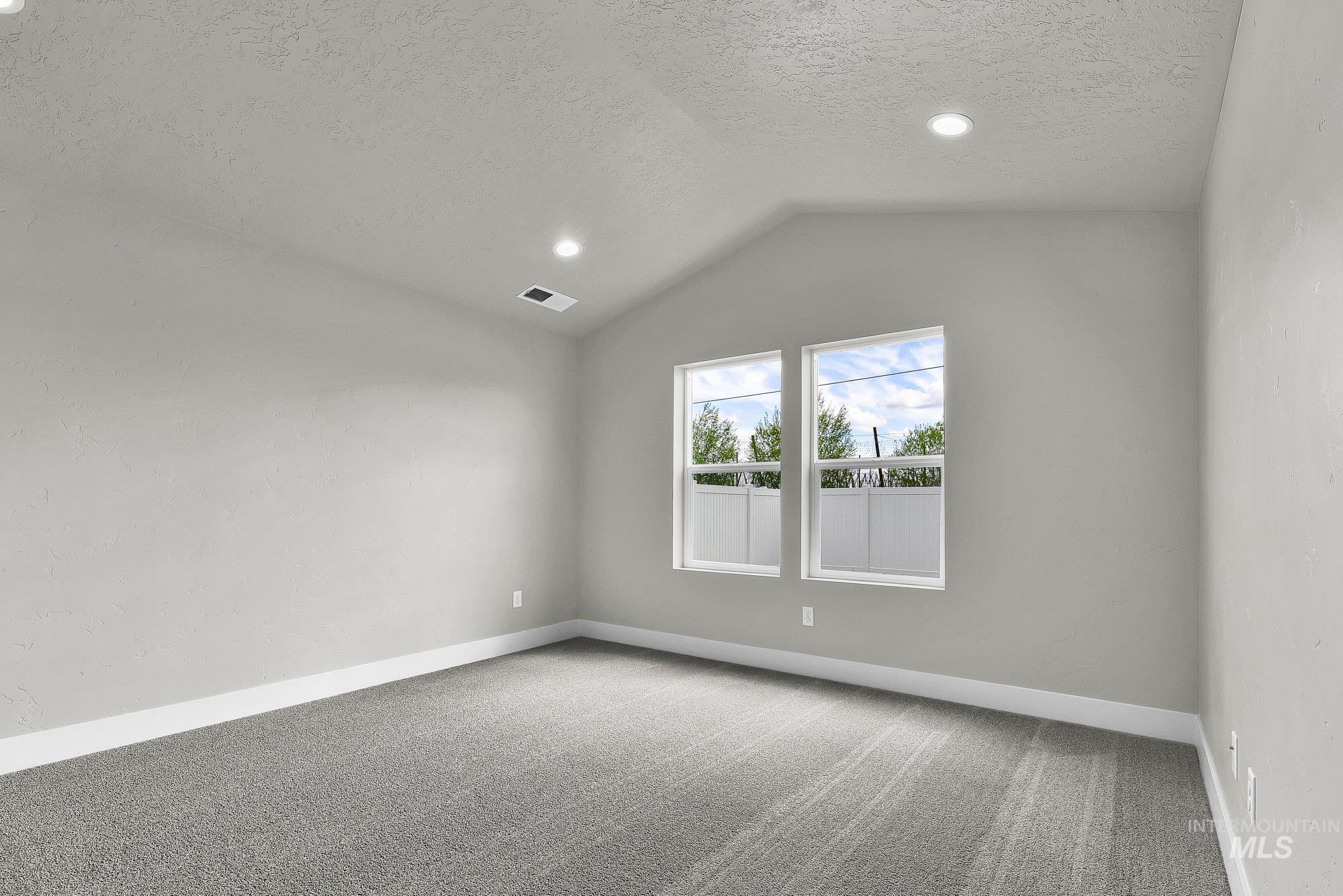 320 North 12th Parma, ID 83660 - Photo 10 of 34 Room featuring a vaulted ceiling with recessed lighting, two windows, carpet flooring, and painted walls