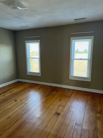 an empty room with wooden floor and a window