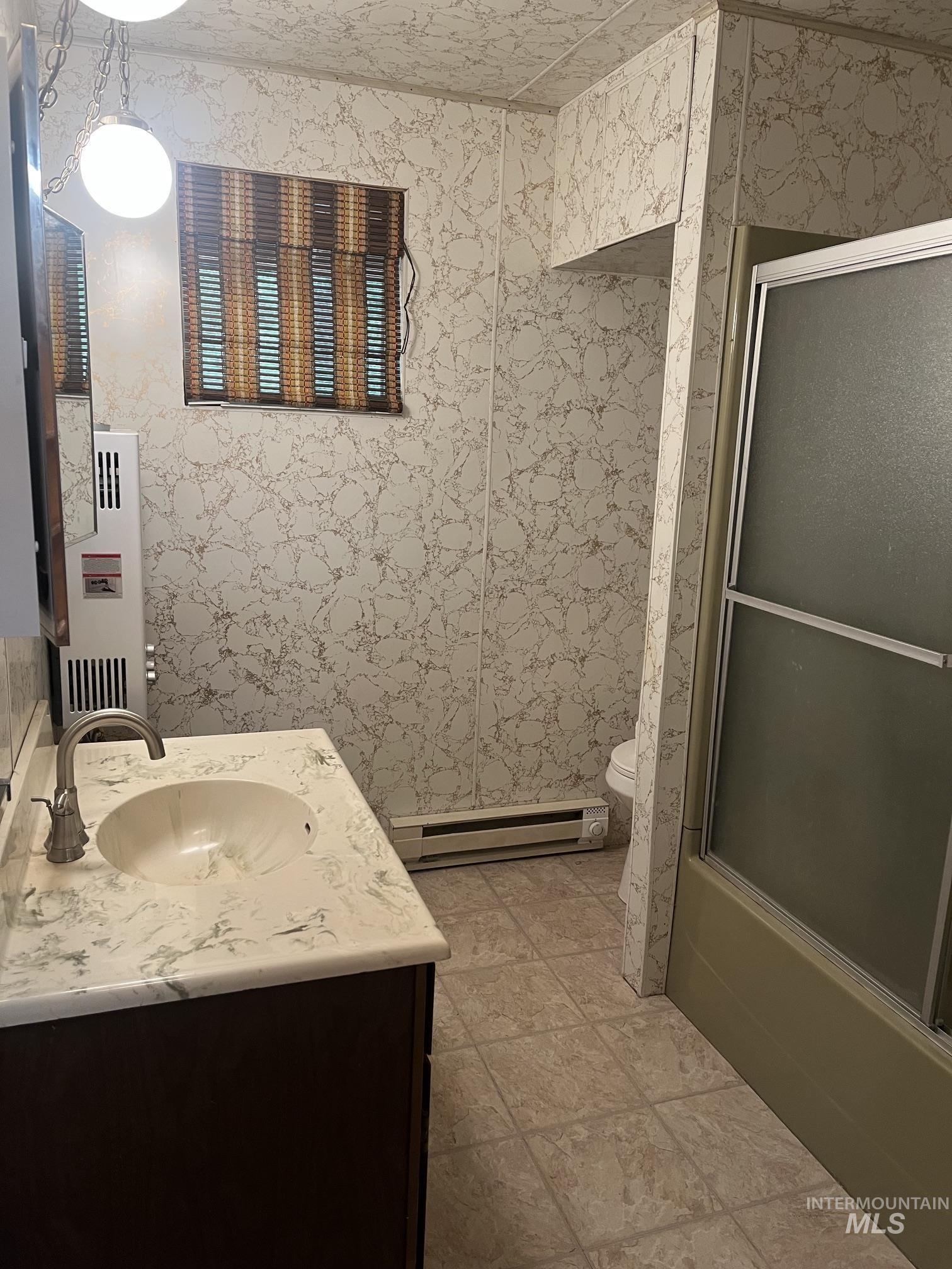 39 Mayflower Mine Road Placerville, ID 83666 - Photo 22 of 36 Bathroom featuring a vanity with an integrated sink and stone-look countertop, dark wood-finish cabinetry, tile flooring, and a shower with a sliding glass door