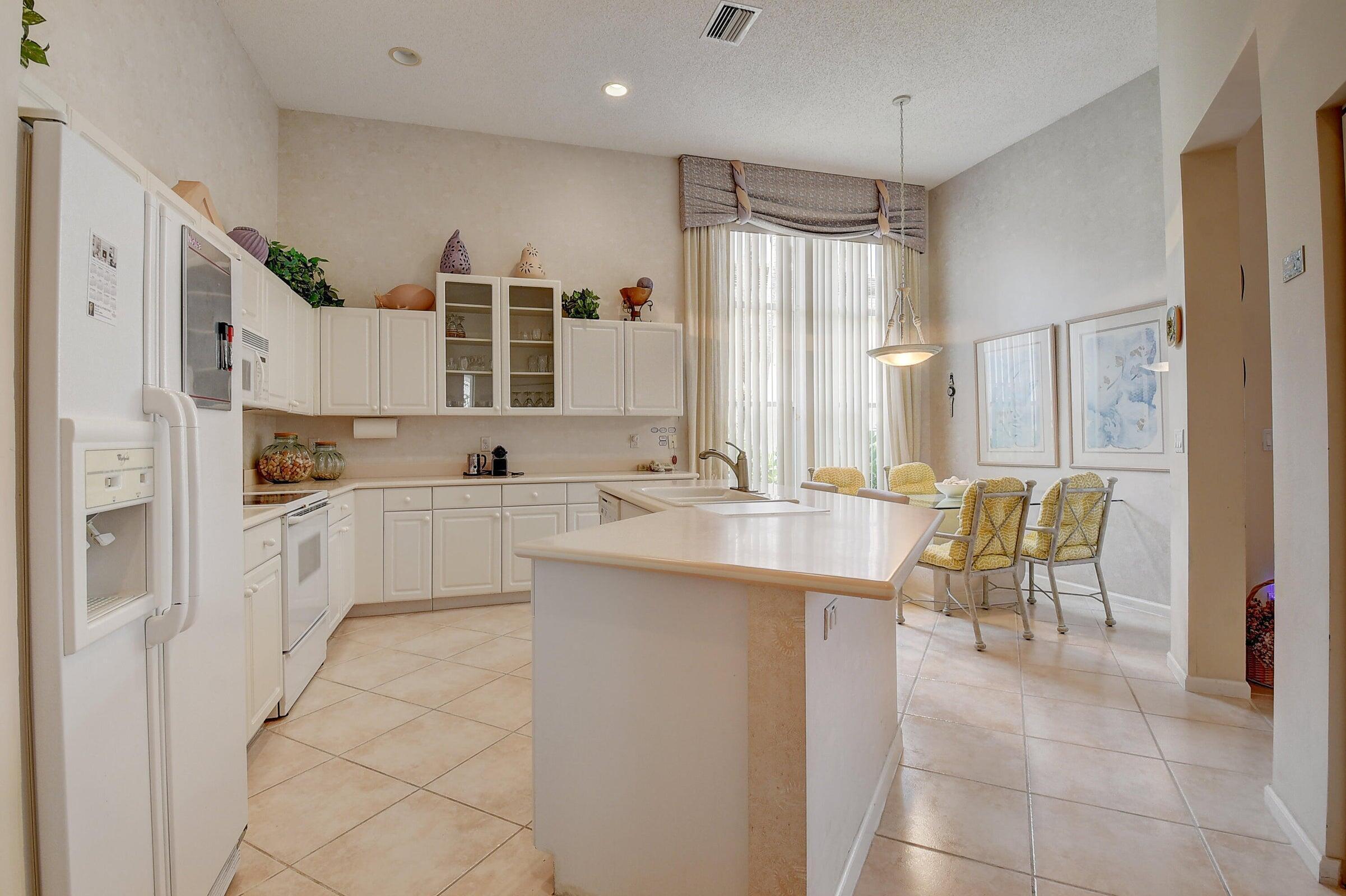 7725 Rockford Road Boynton Beach, FL 33472 - Photo 10 of 47 a large white kitchen with cabinets and chairs