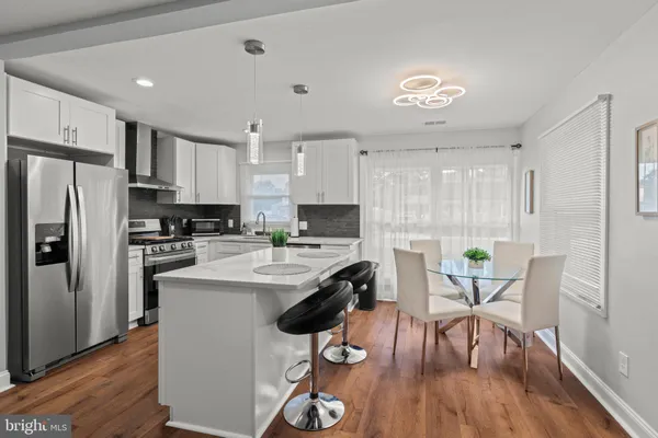 a kitchen with stainless steel appliances granite countertop a stove a refrigerator a sink a dining table and chairs