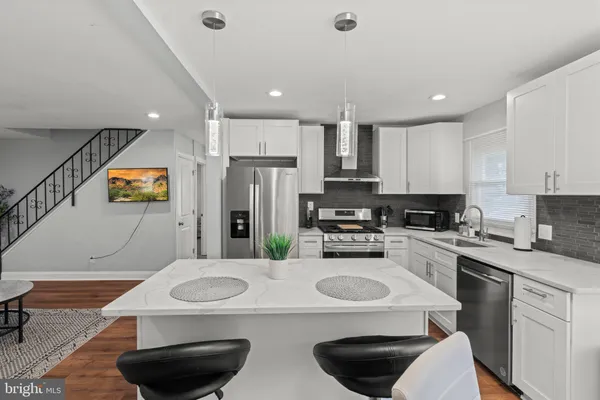 a kitchen with stainless steel appliances granite countertop a sink a stove a refrigerator and white cabinets with wooden floor