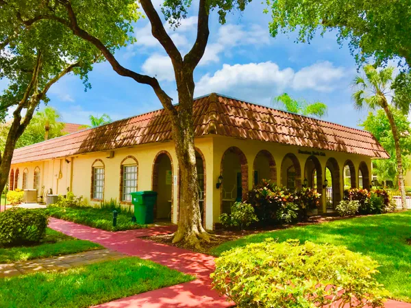 a view of yellow house with a yard and plants