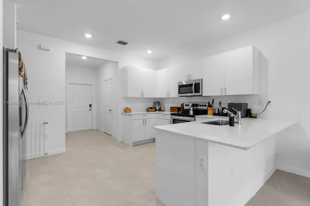 a kitchen with stainless steel appliances a refrigerator sink and white cabinets