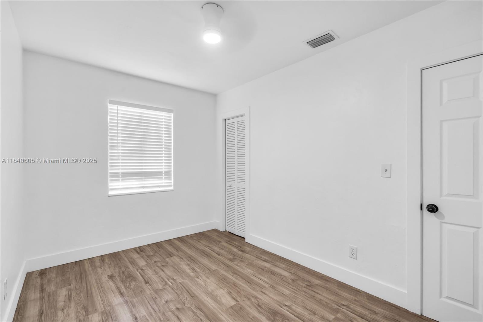 1050 Superior Street Opa-Locka, FL 33054 - Photo 13 of 20 a view of an empty room with wooden floor and a window