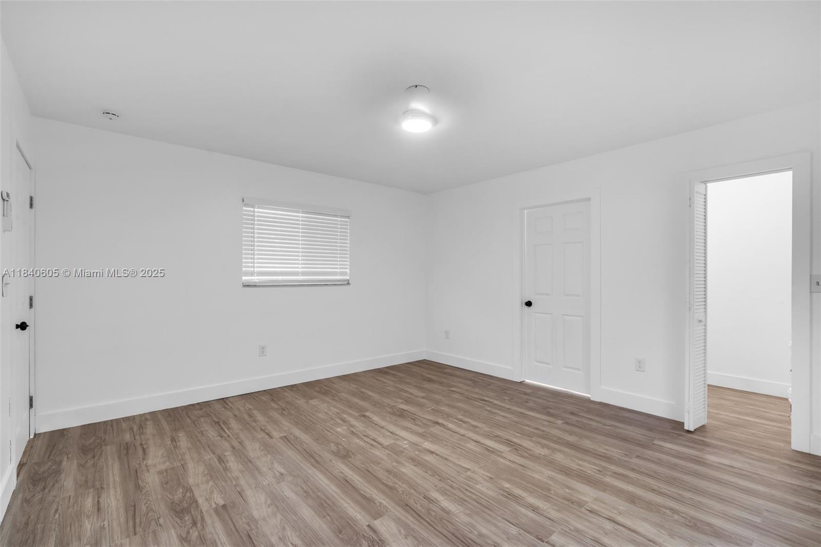 1050 Superior Street Opa-Locka, FL 33054 - Photo 9 of 20 an empty room with wooden floor and windows