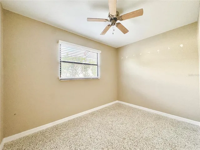 an empty room with a window and a fan
