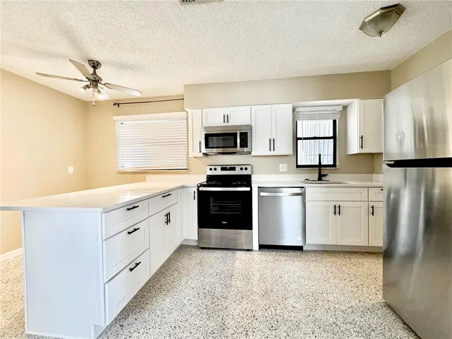 a kitchen with white cabinets and stainless steel appliances