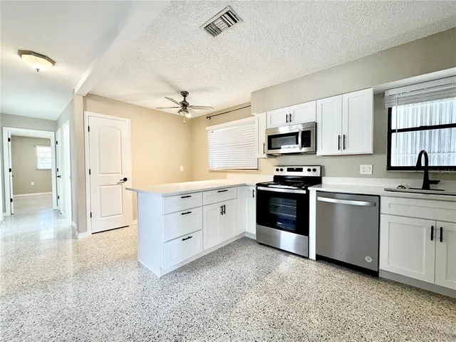 a kitchen with cabinets stainless steel appliances and a window