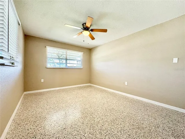 an empty room with windows and ceiling fan