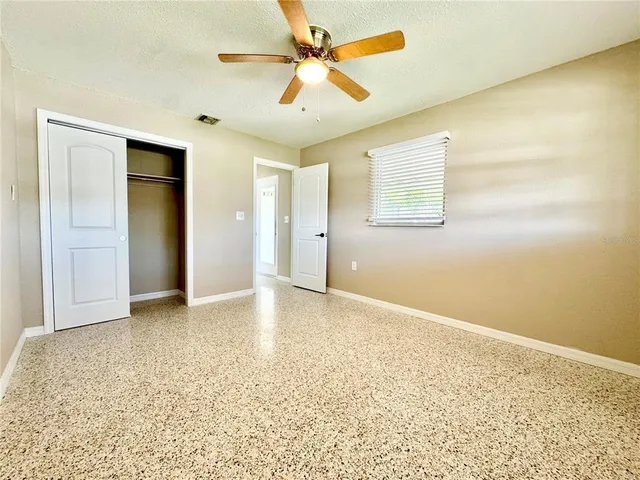 an empty room with a ceiling fan and carpet