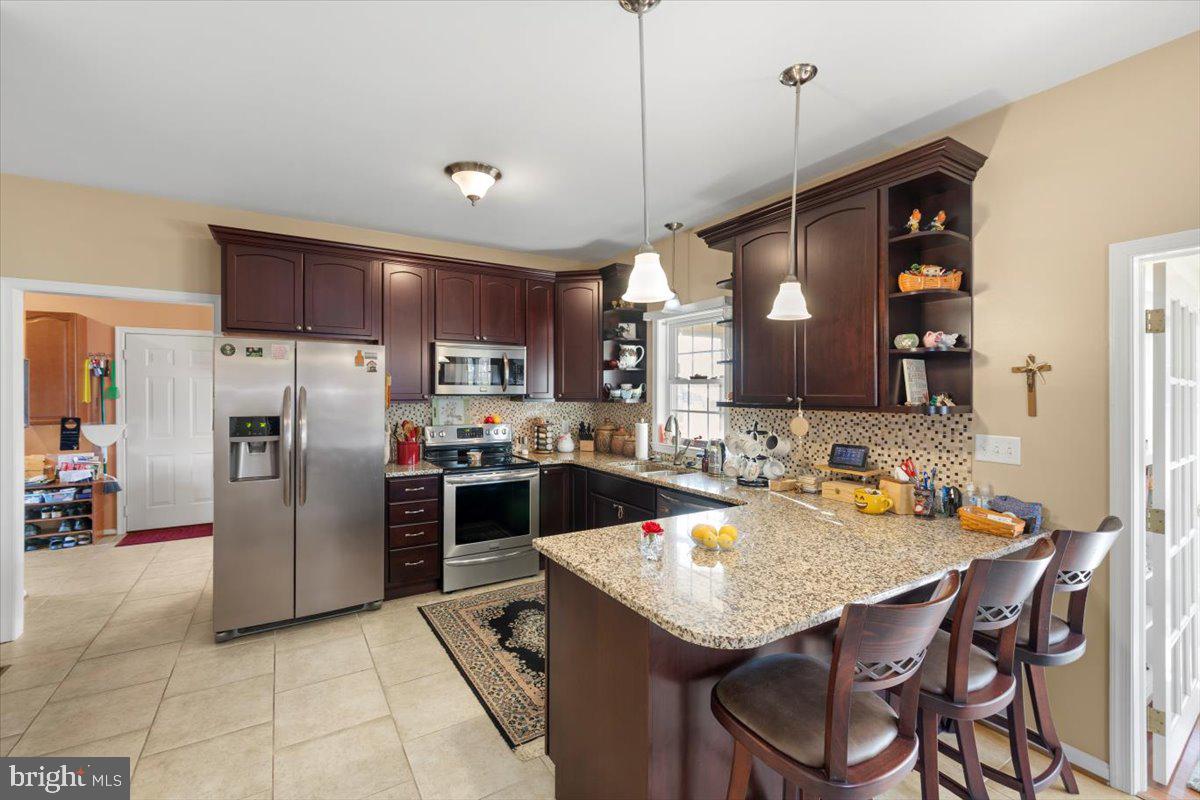 334 Friendship Lane Gettysburg, PA 17325 - Photo 22 of 64 a kitchen with stainless steel appliances granite countertop a stove a refrigerator a kitchen island a sink a dining table and chairs