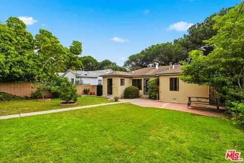 a front view of a house with a garden and trees