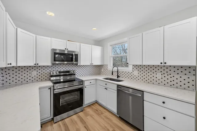 a kitchen with granite countertop white cabinets sink and stainless steel appliances