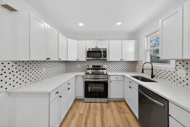 a kitchen with granite countertop a sink dishwasher a stove and a microwave oven with cabinets