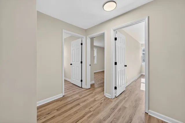 a view of a hallway with wooden floor and a bathroom