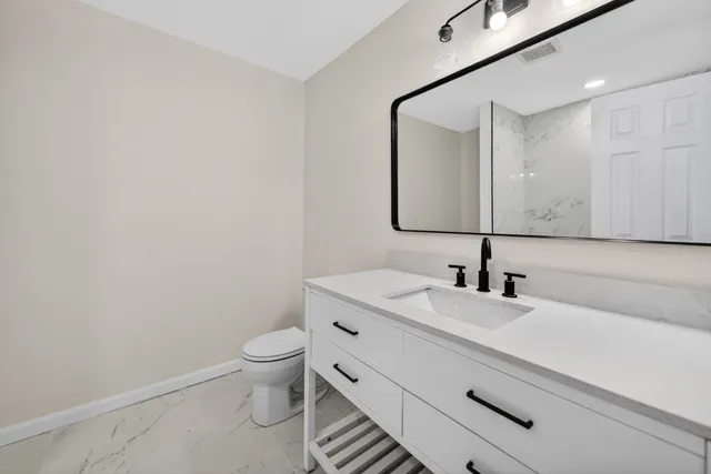 a bathroom with a granite countertop sink a toilet and a mirror