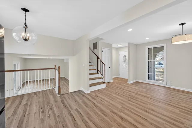 a view of empty room with wooden floor fan and window