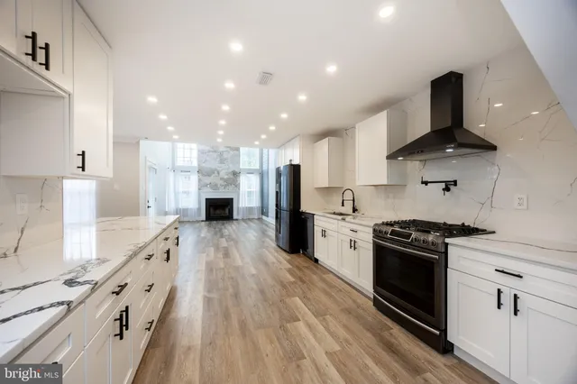 a large kitchen with stainless steel appliances granite countertop a stove and a wooden floors