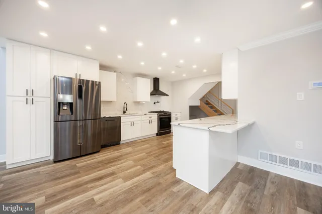a kitchen with stainless steel appliances kitchen island granite countertop a refrigerator and a sink
