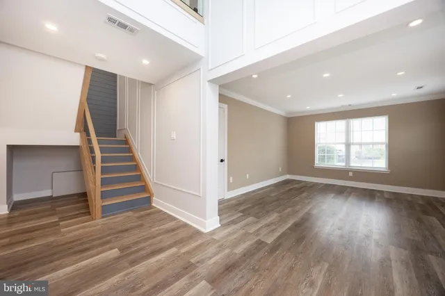 a view of an empty room with wooden floor and stairs