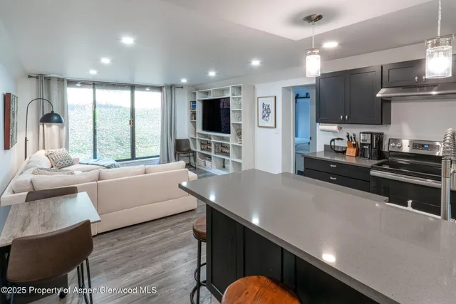 a living room with stainless steel appliances furniture large window and a view of kitchen