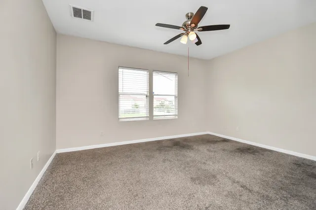 an empty room with a window and a fan