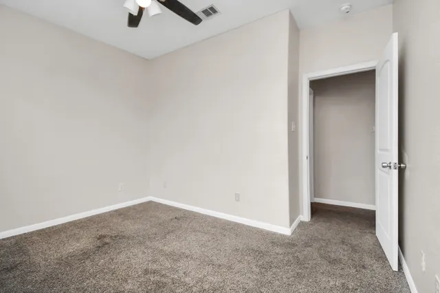 an empty room with a ceiling fan and carpet