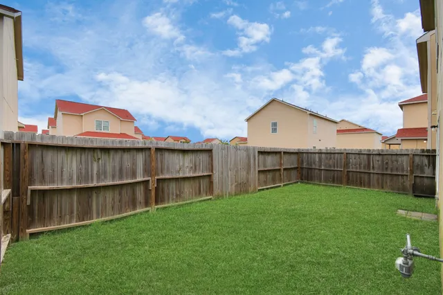 a view of a backyard with a large tree and wooden fence