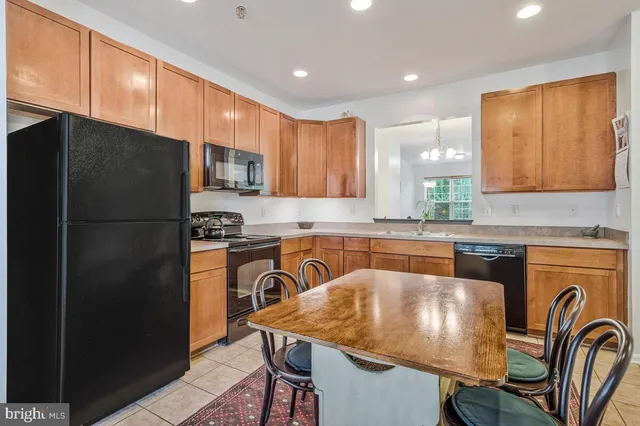 a kitchen with stainless steel appliances granite countertop a refrigerator a sink a stove a dining table and chairs